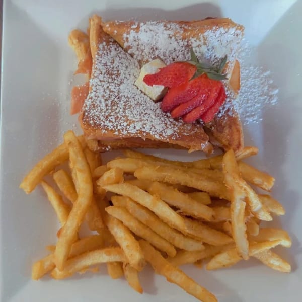 BLT's Breakfast Lunch & Takeout's French toast with powdered sugar, strawberries, and a side of fries.