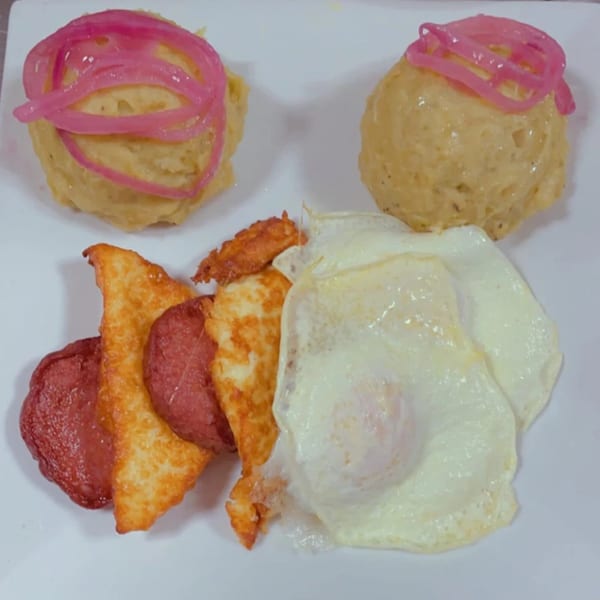 BLT's breakfast plate with two mounds of mofongo topped with pickled onions, fried cheese, salami, and a fried egg.
